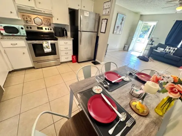 Kitchen with a stove and fridge, dining table set for four